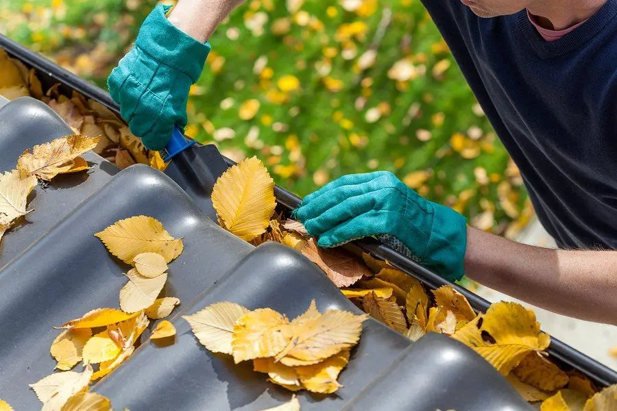 Hands working at the edge of a residential gutter